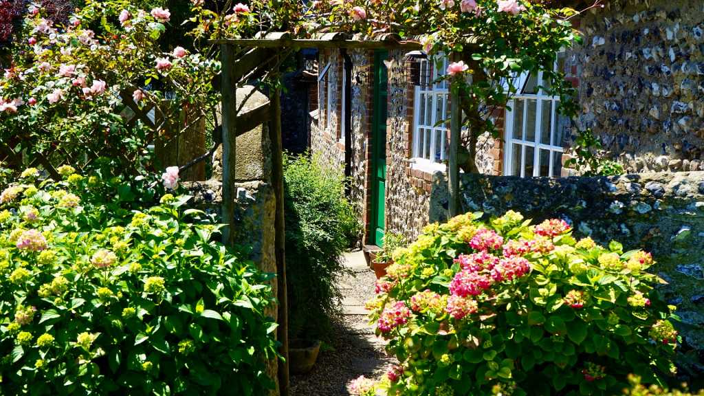 garden with garden path, trellis archway and flowers in flowerbeds.